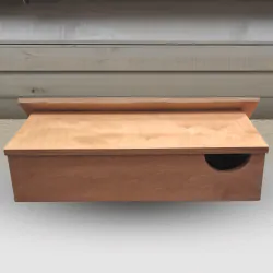 brown wood colour swift nest box hanging under eaves of white house
